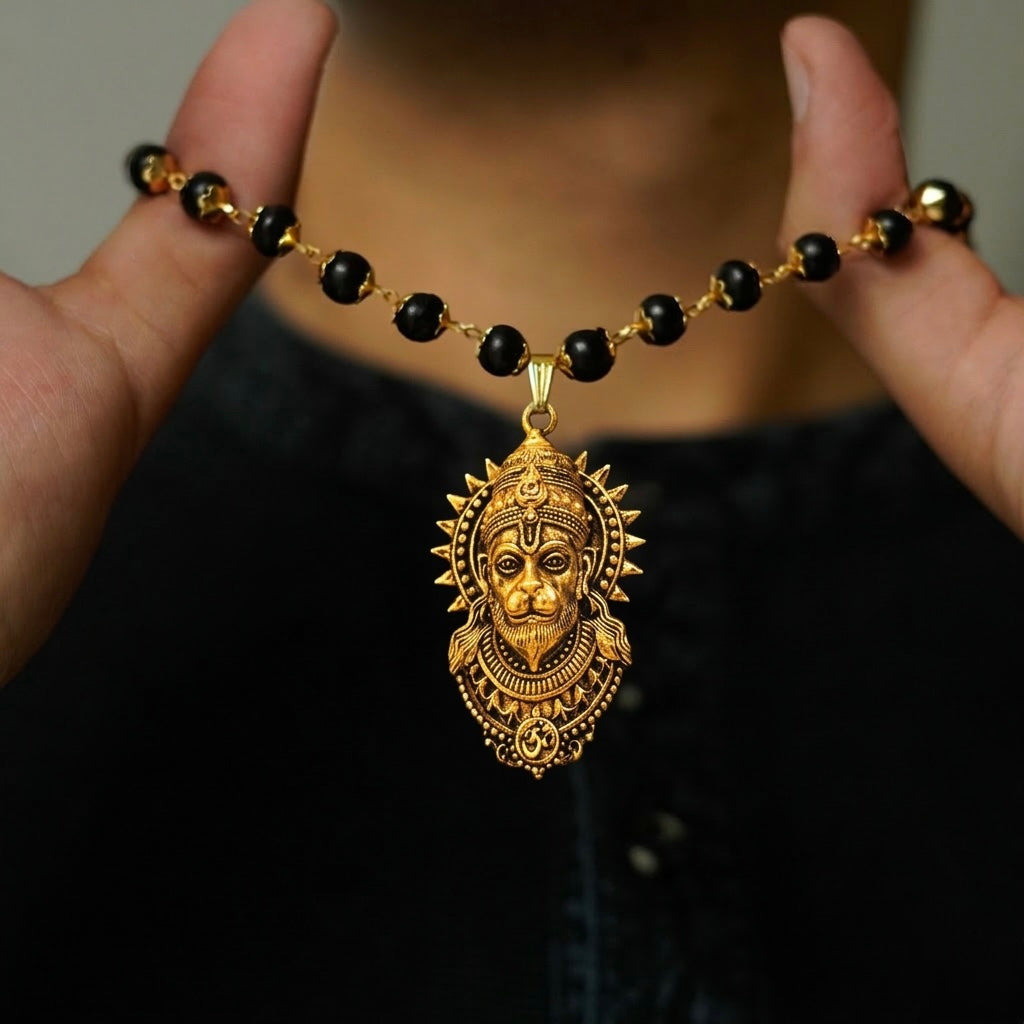Close-up of black beaded Karungali mala with golden Hanuman pendant