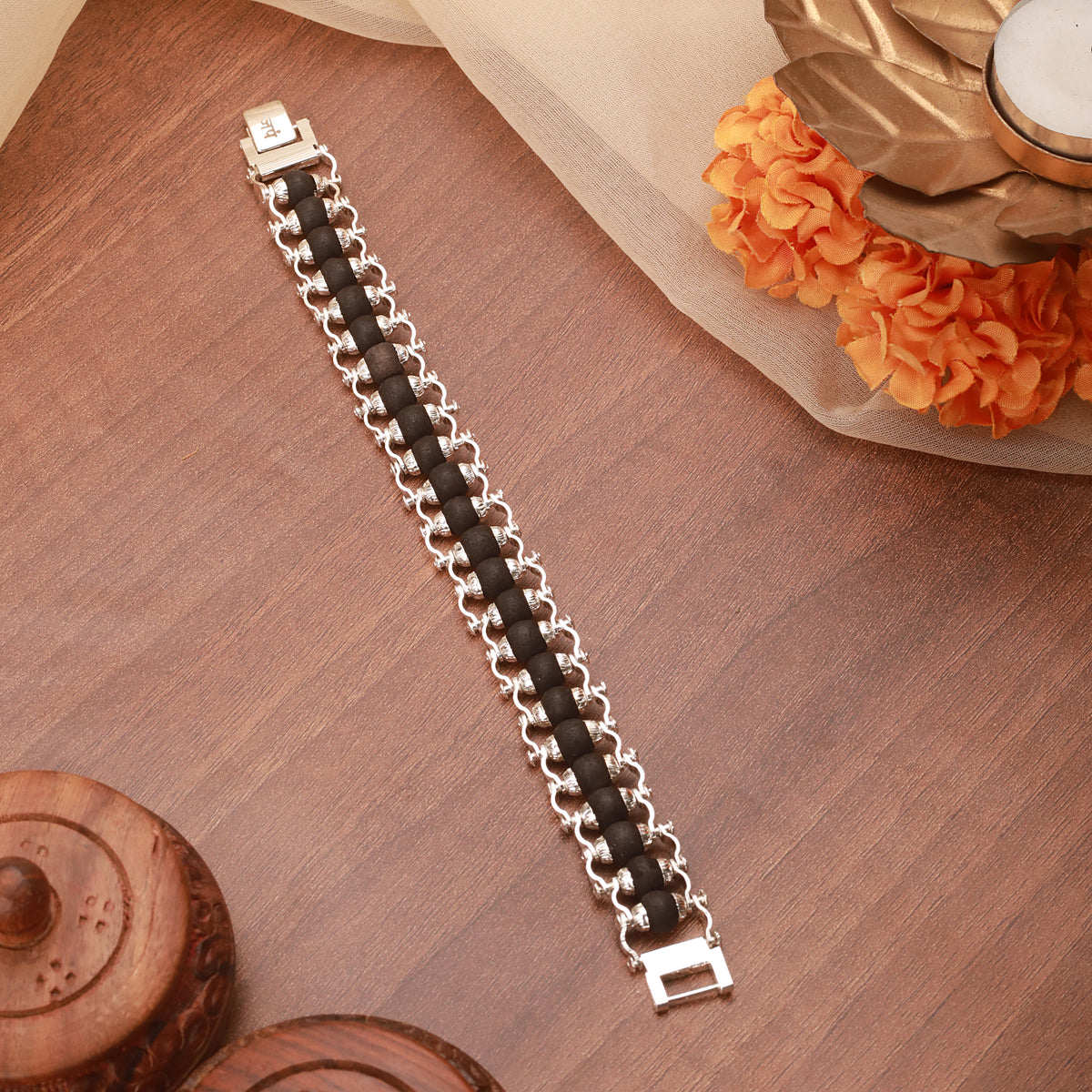 Karungali black beaded silver bracelet for men displayed on a wooden surface with decorative background